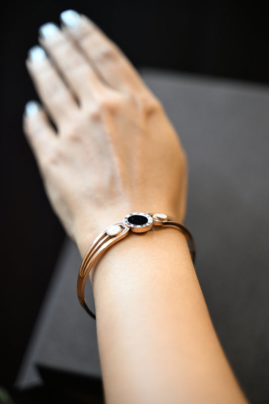 Close-up of a wrist wearing a bracelet with a dark central stone on a dark background