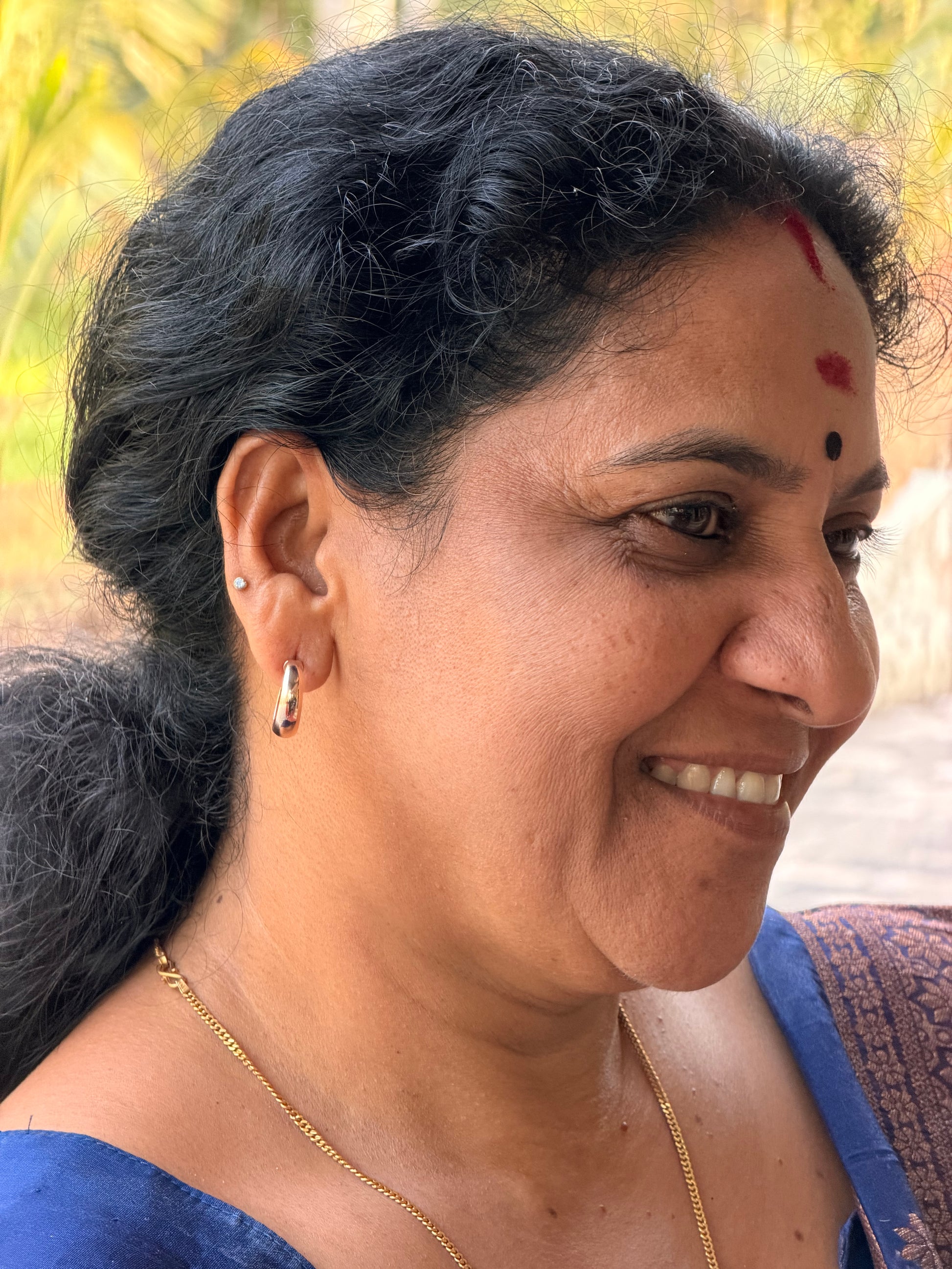 Close-up of a person with dark hair and traditional makeup, wearing a blue garment.